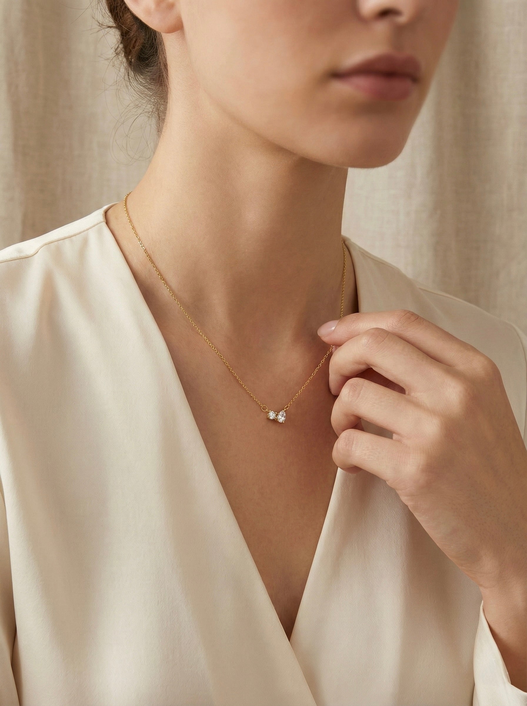 Side view of anti-tarnish gold lunara bow pendant necklace with fine chain on model styled for office wear