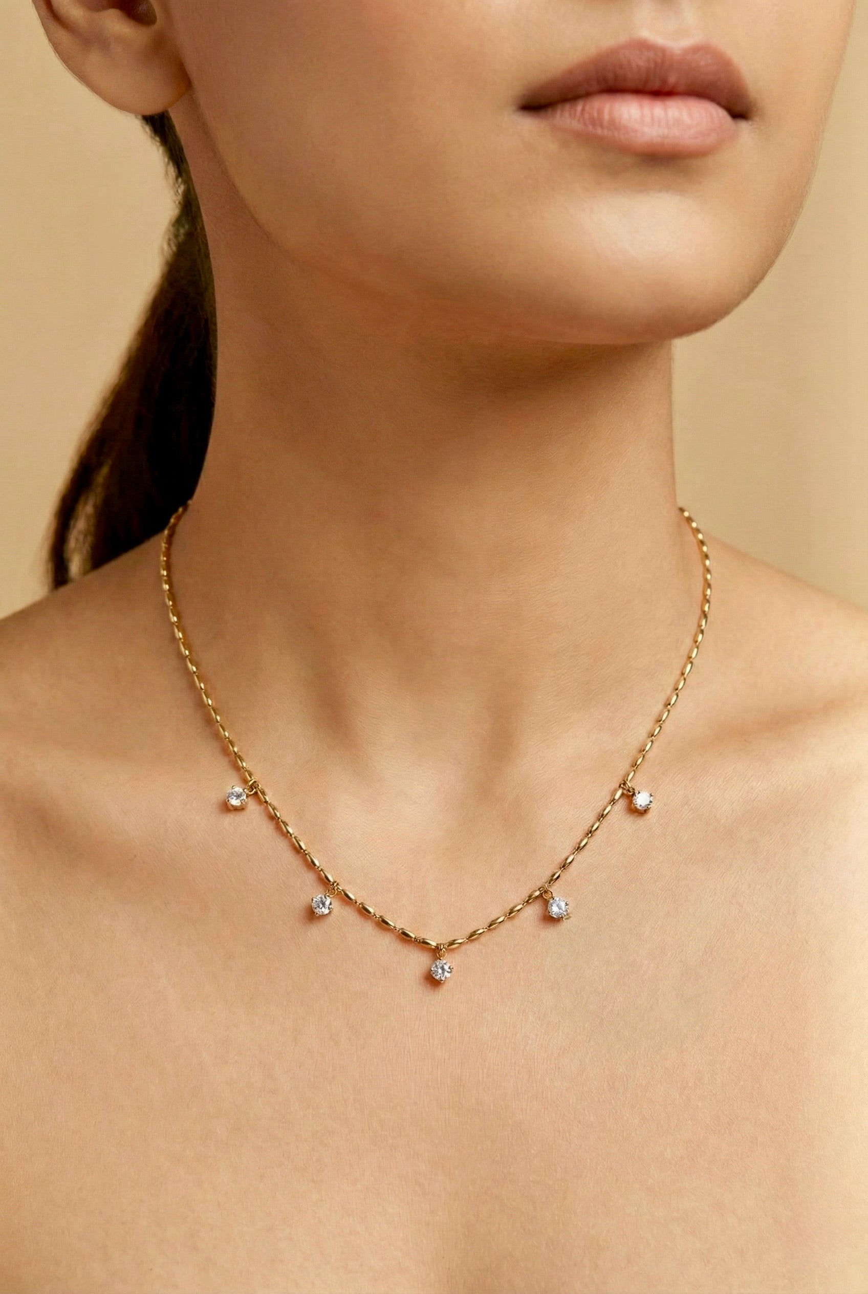 Close-up detailing of Lyra CZ drop stones on gold anti-tarnish necklace styled on model