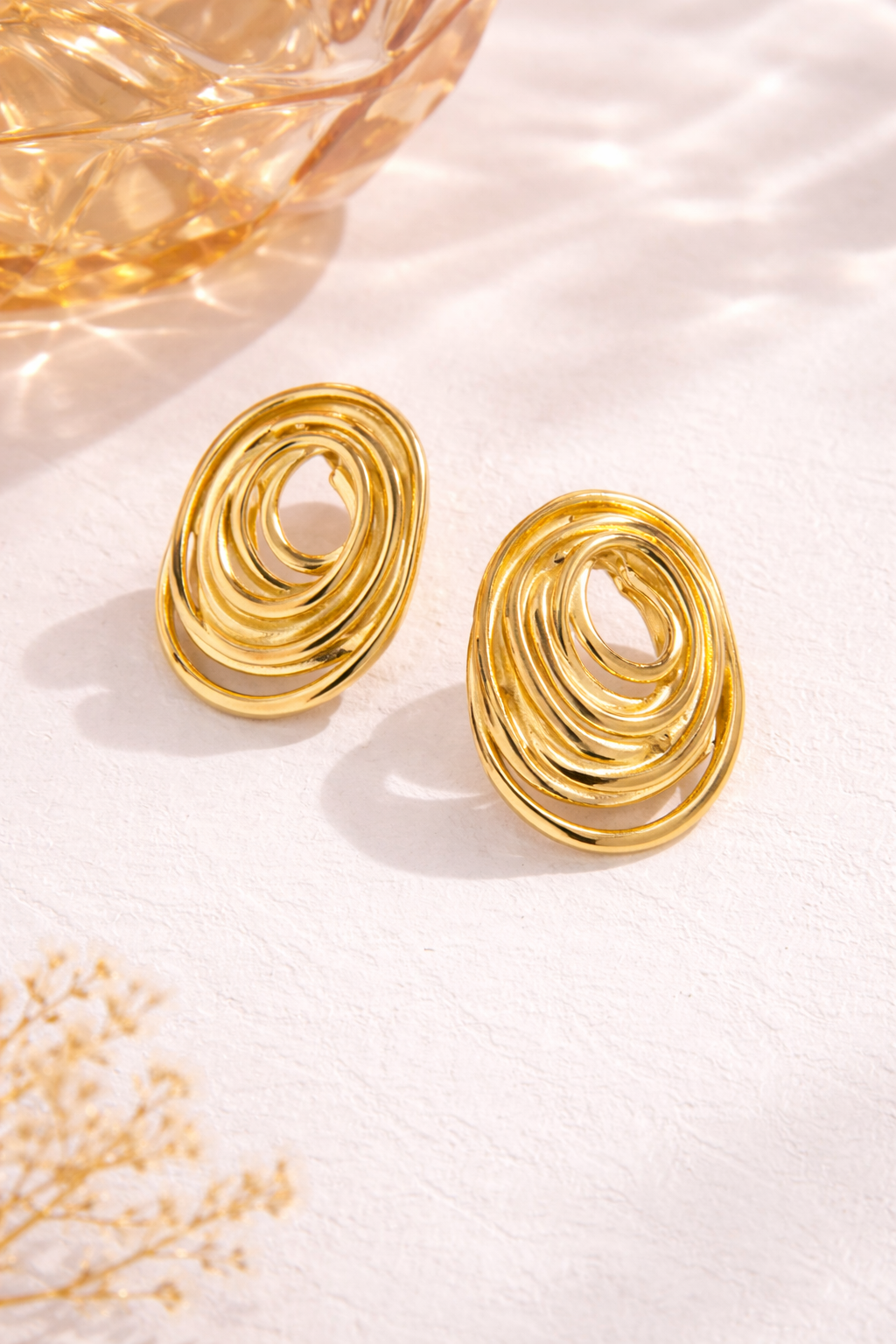 Close-up of Aurelia Swirl anti-tarnish gold statement earrings showing abstract swirl design