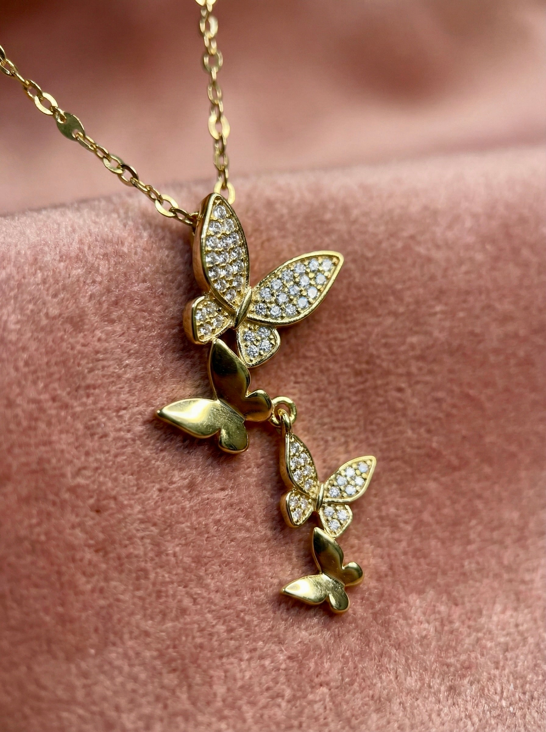 Close-up of gold Aurethia butterfly drop pendant with cubic zirconia sparkle