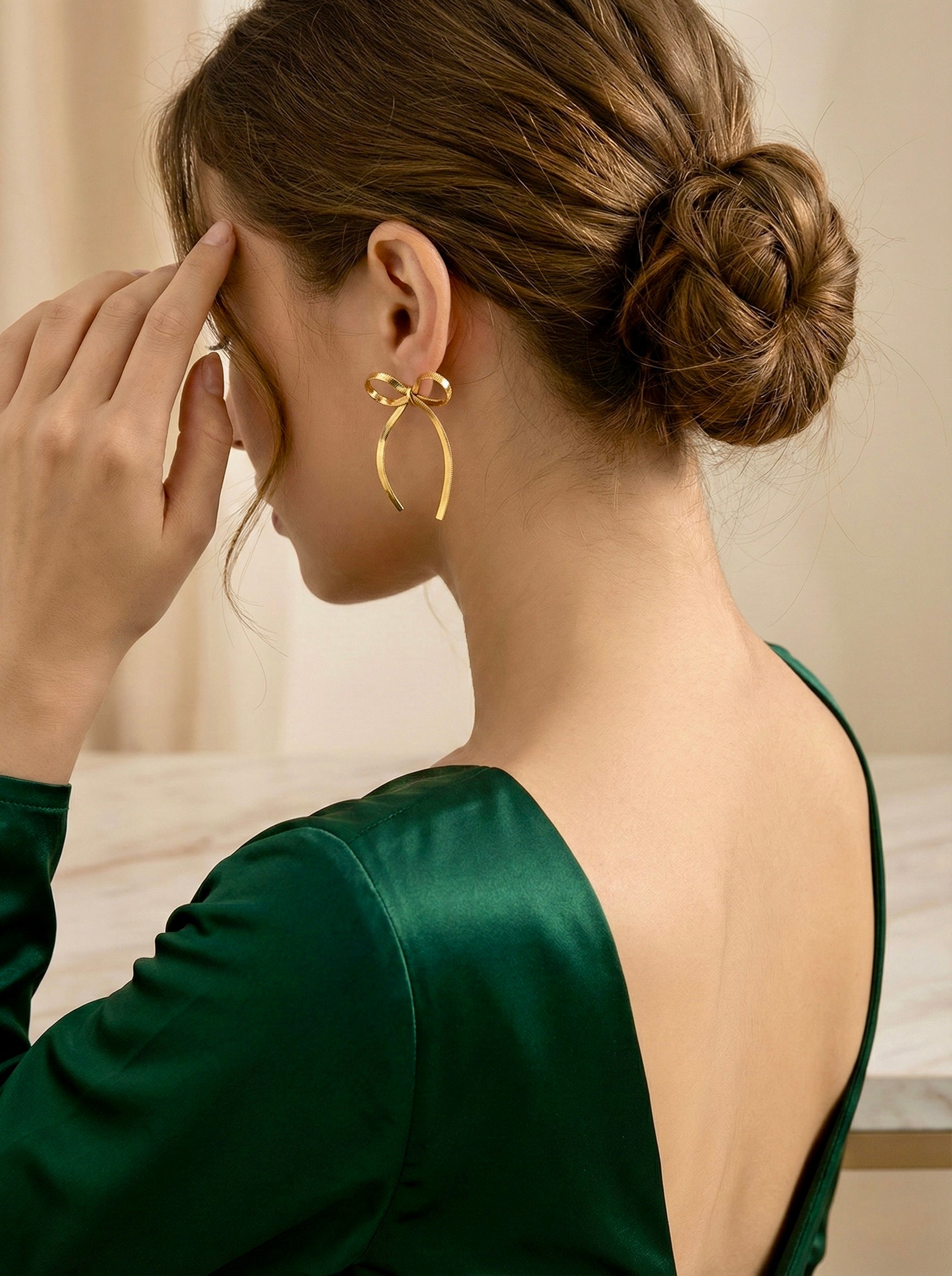Elegant gold bow drop earrings on model for evening statement style