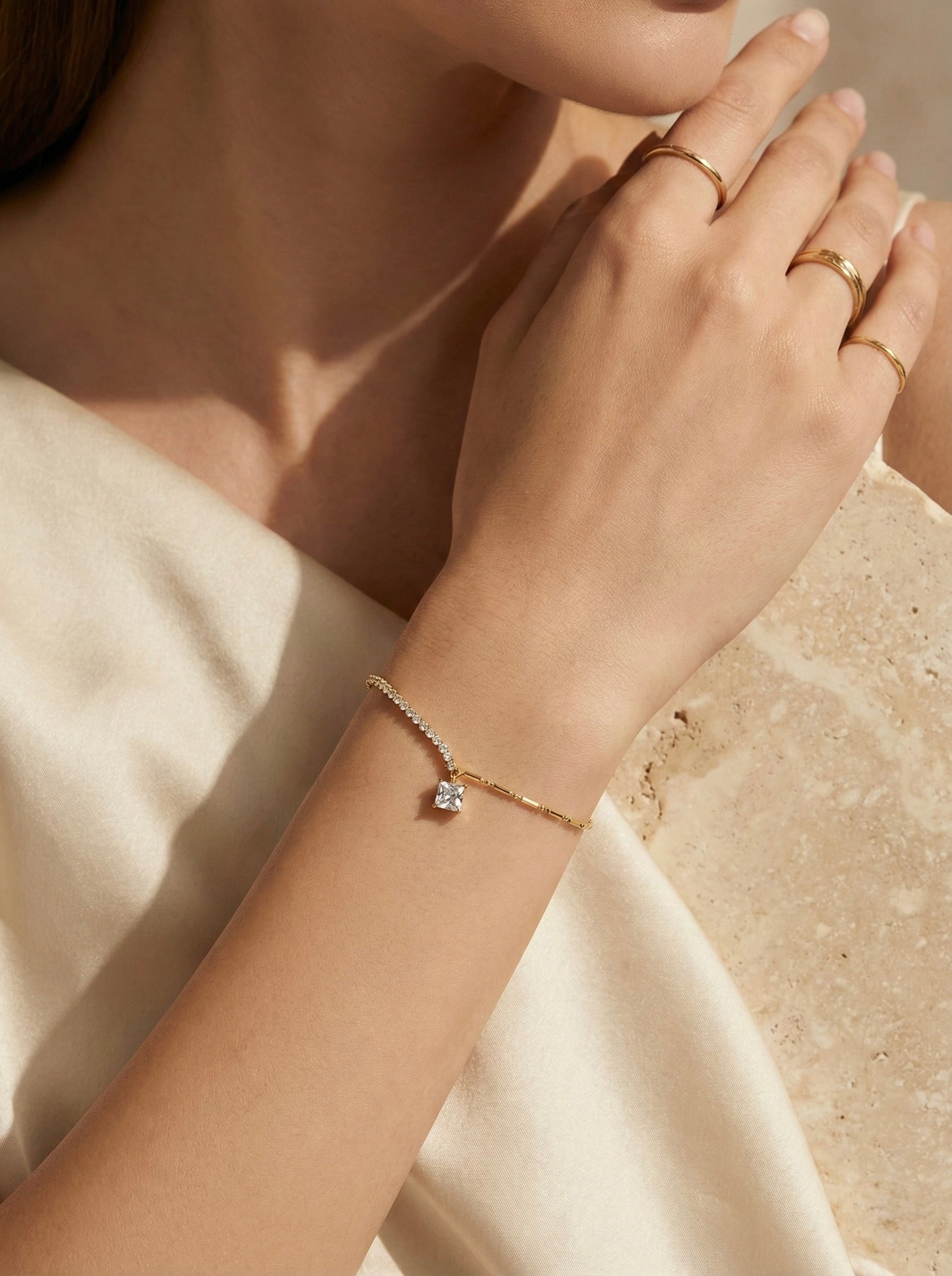 Close-up of sparkling square cubic zirconia charm on gold anti-tarnish celestia bracelet