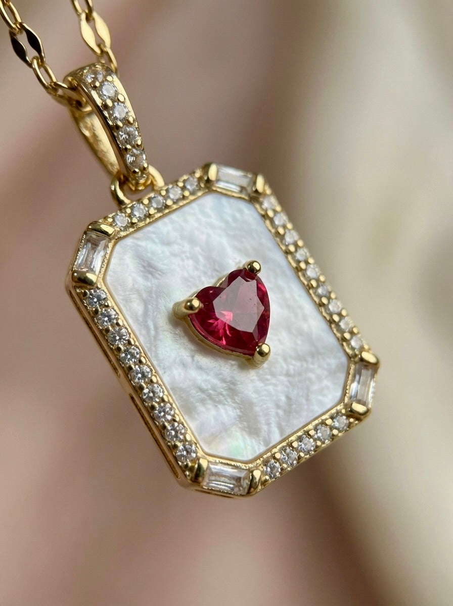 Close up side view of anti-tarnish gold emerelle heart halo necklace with crimson red/pink gemstone centerpiece