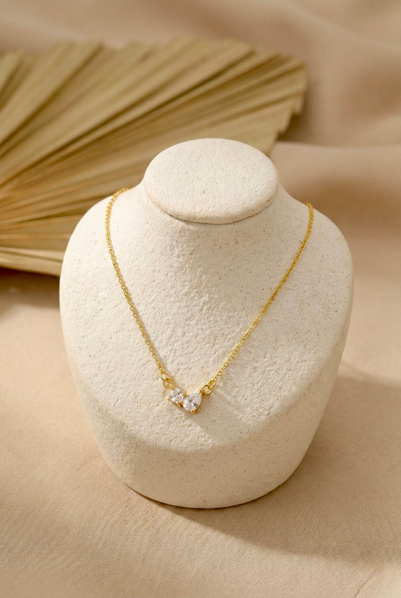 Close-up of gold lunara bow CZ pendant necklace with sparkling cubic zirconia stones