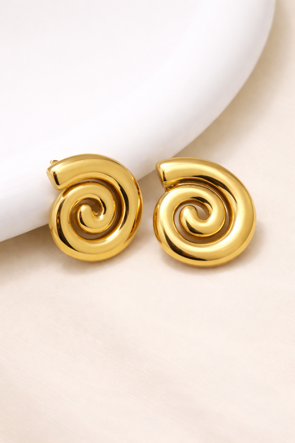 Close-up of Helix anti-tarnish gold spiral stud earrings showing textured swirl design