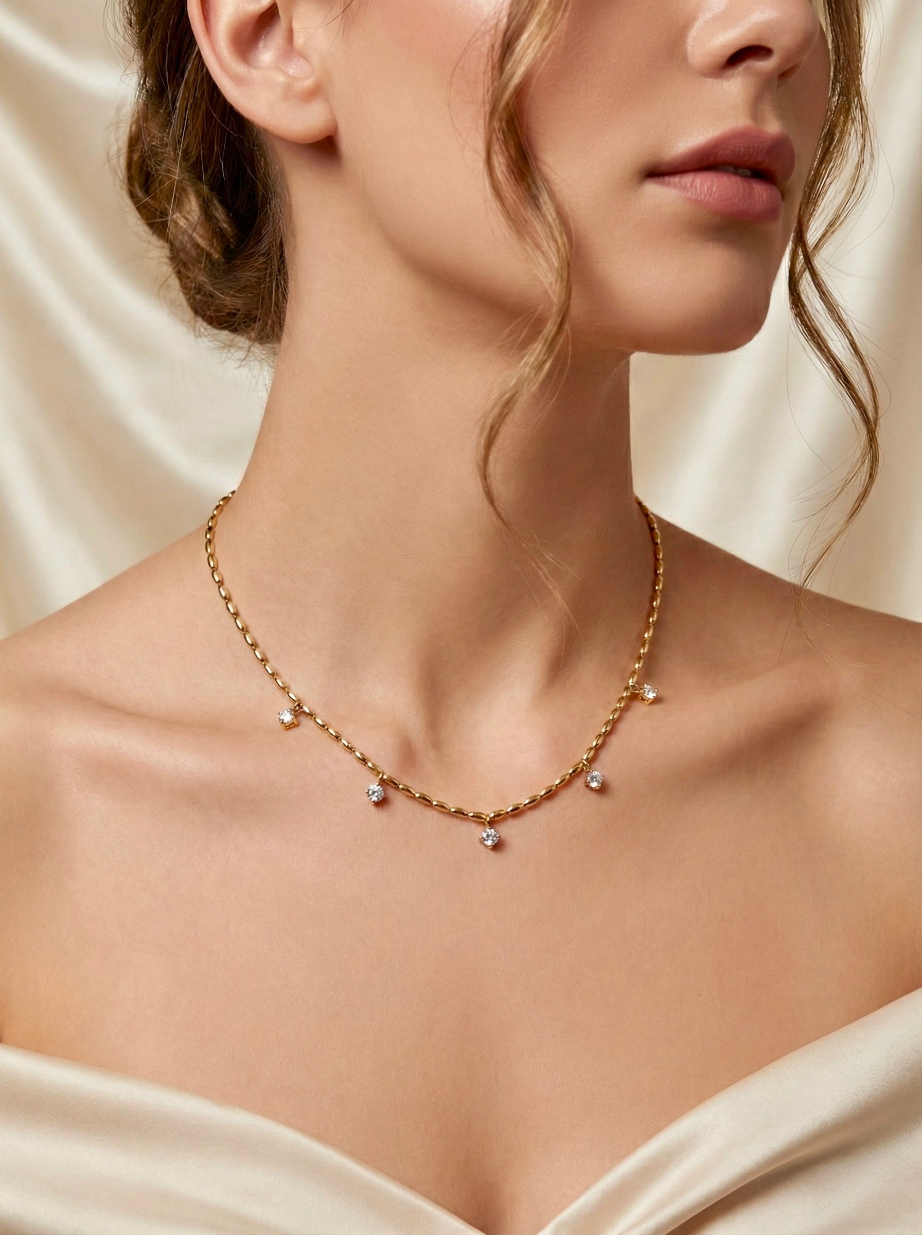 Front view of anti-tarnish gold Lyra CZ drop necklace on fine chain styled on model for evening styling