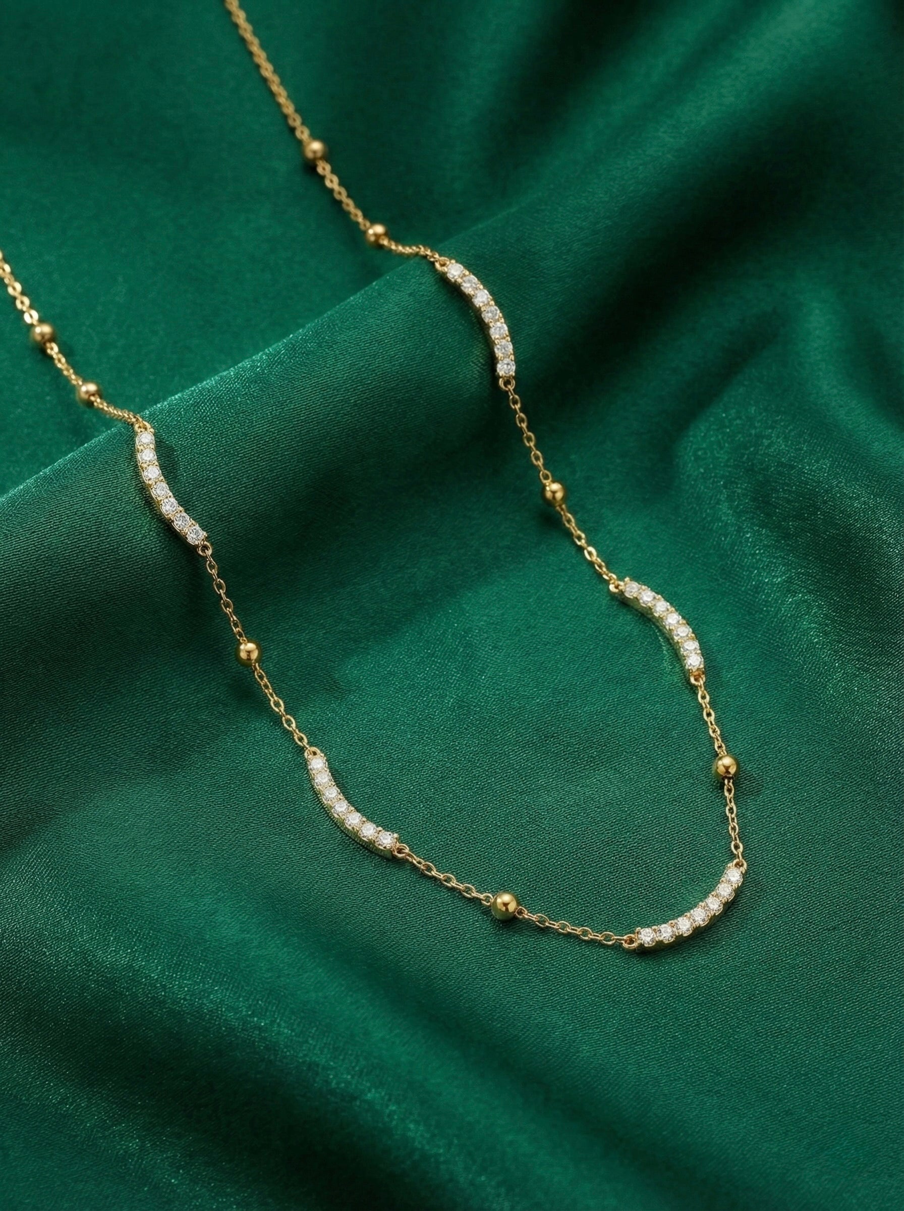 Minimal gold caelisse curve CZ necklace styled on neutral surface for everyday elegance