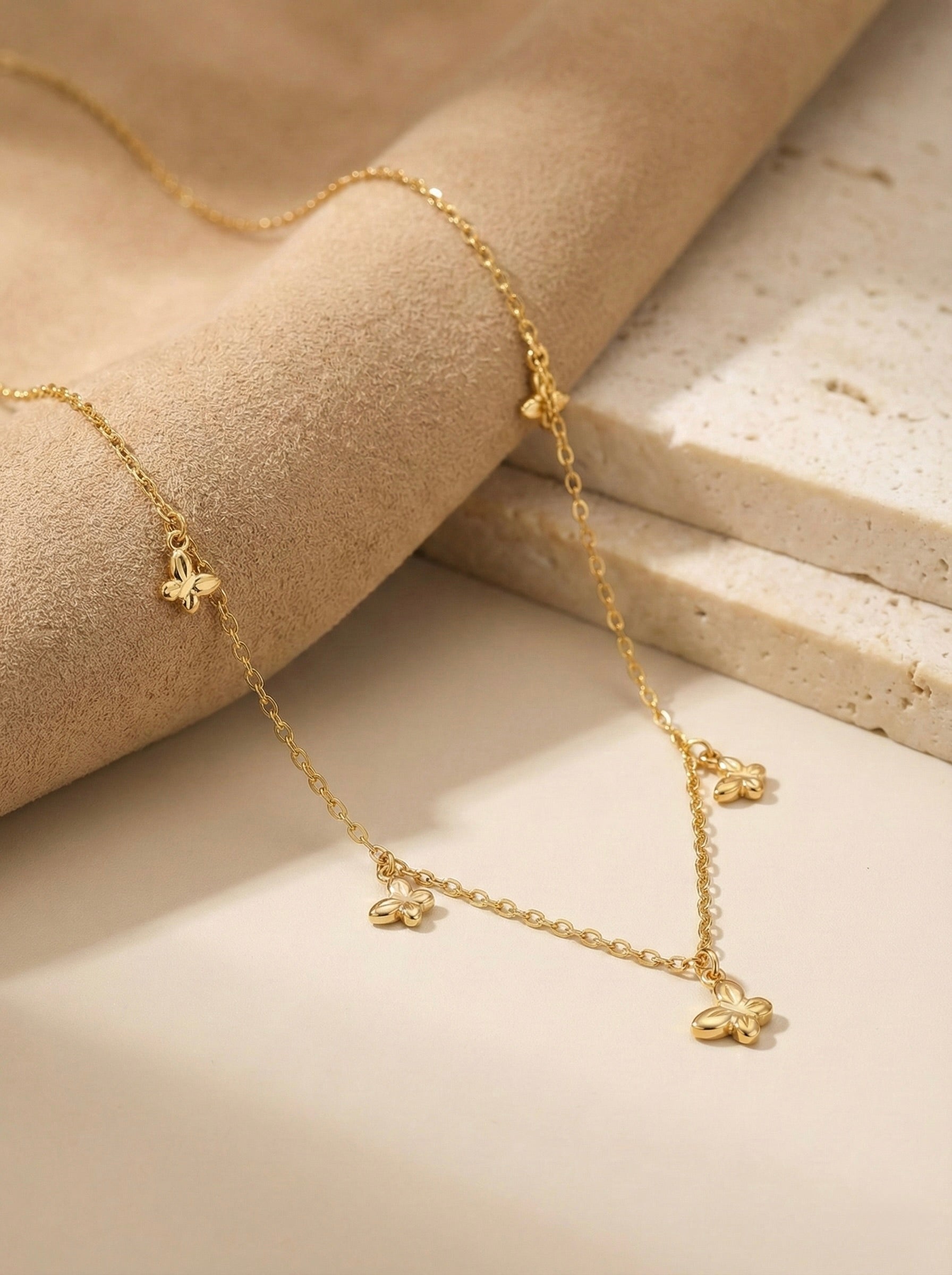Minimal gold Elara butterfly charm necklace styled on neutral surface for everyday elegance