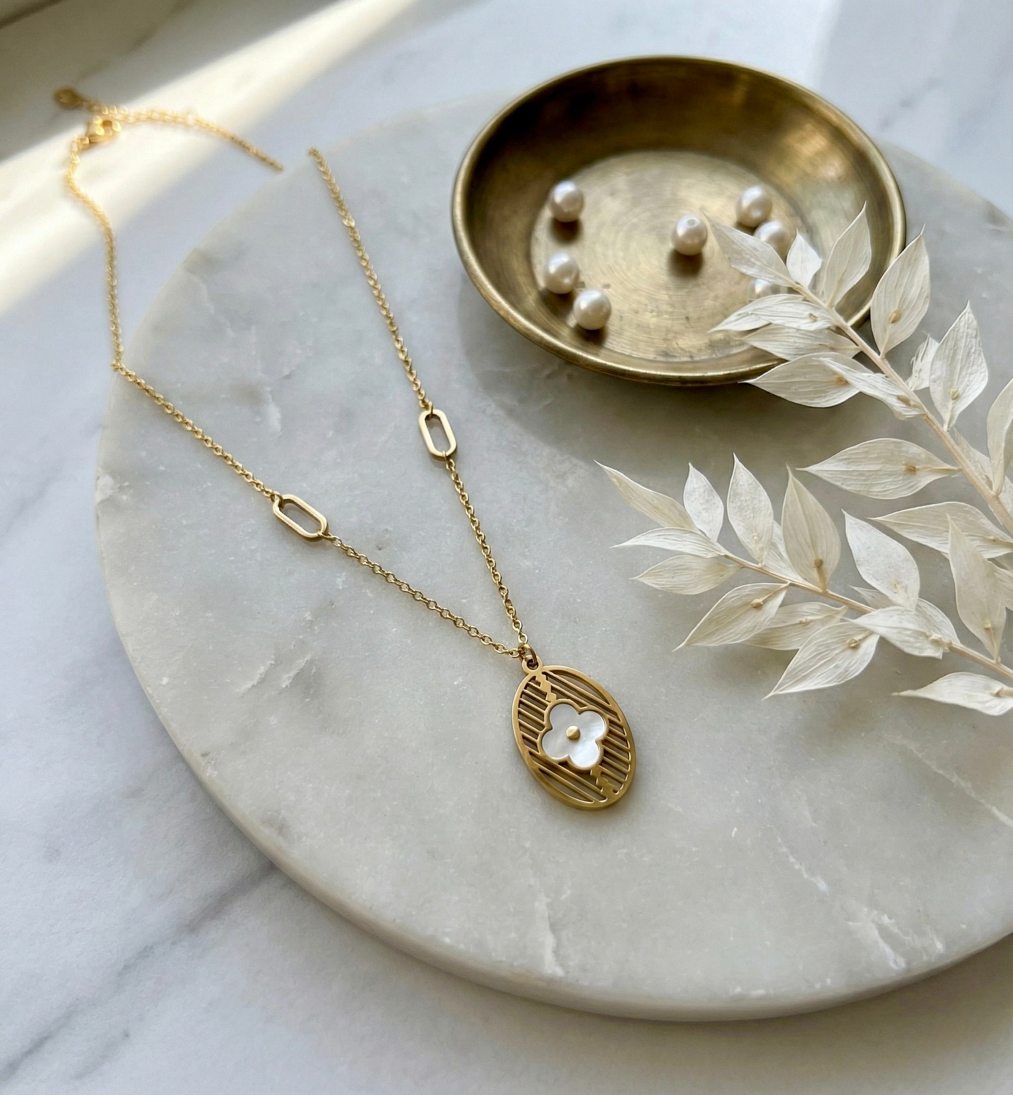 Minimal gold eliora floral medallion necklace styled on fabric for everyday elegance