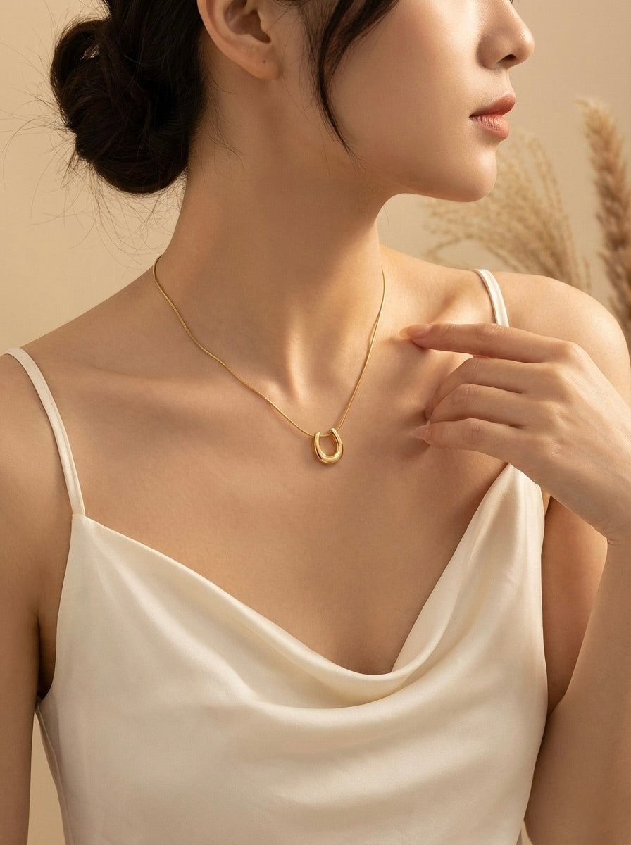 Minimal gold U-shaped necklace styled on model for everyday elegance