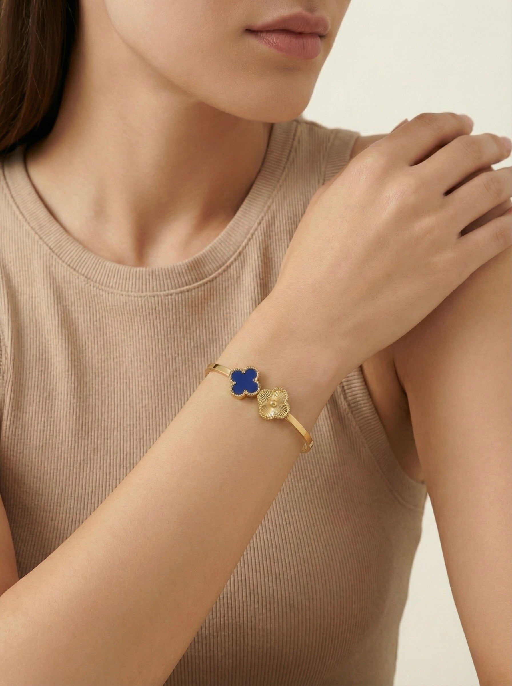 Close-up of Nolira twin clover gold cuff bracelet showing enamel and polished clover charms styled on model for everyday elegance