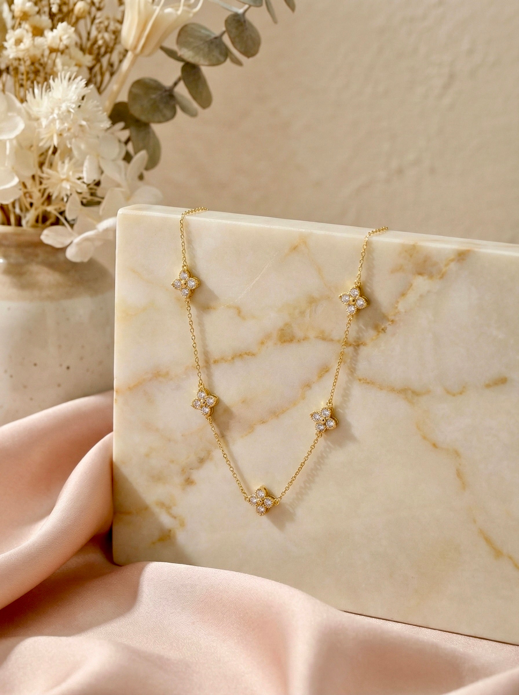 Close-up of Noor floral station gold necklace showing CZ flower charms