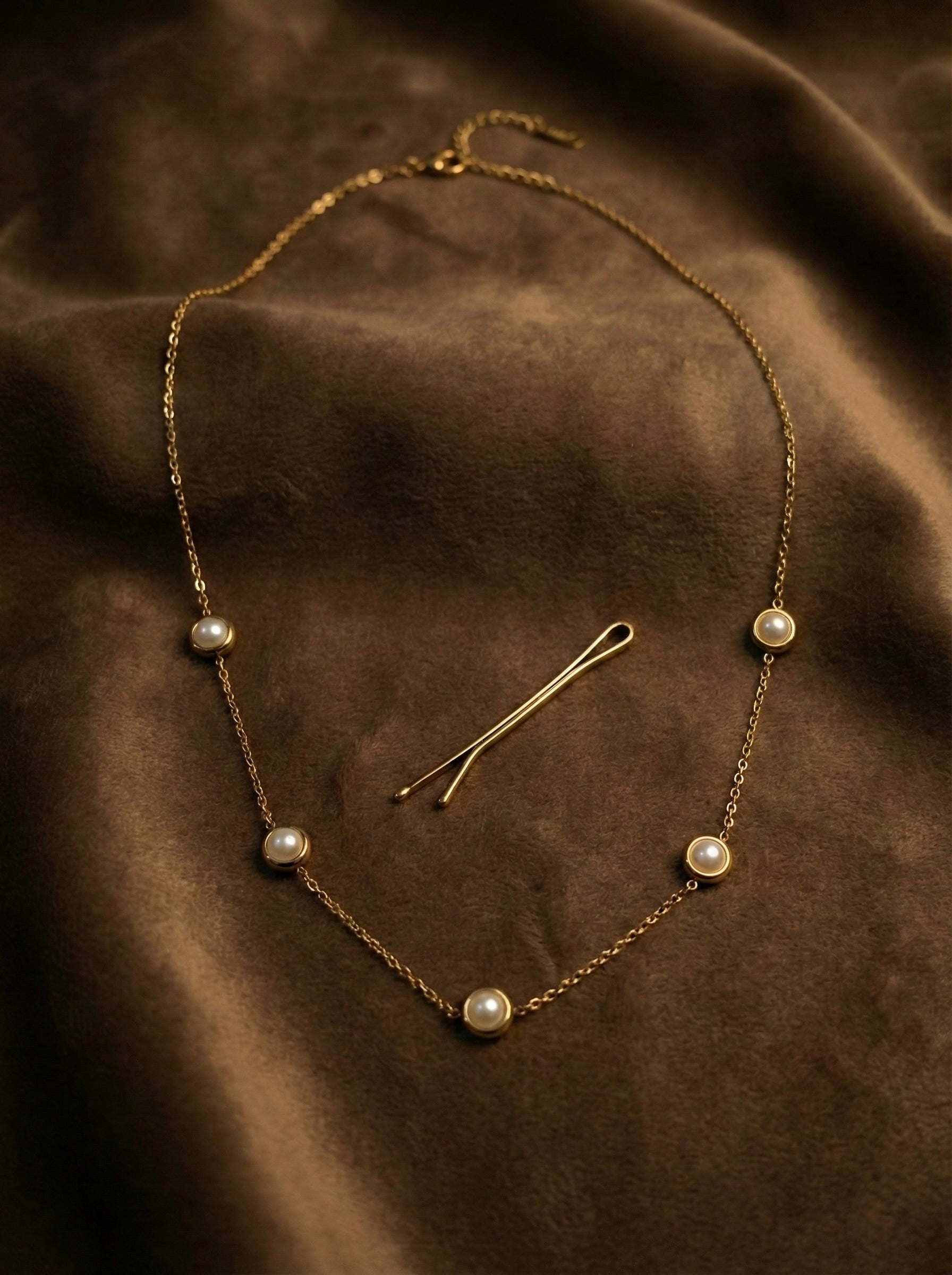 Flatlay of Perlisse Aura pearl station gold necklace styled for everyday elegance