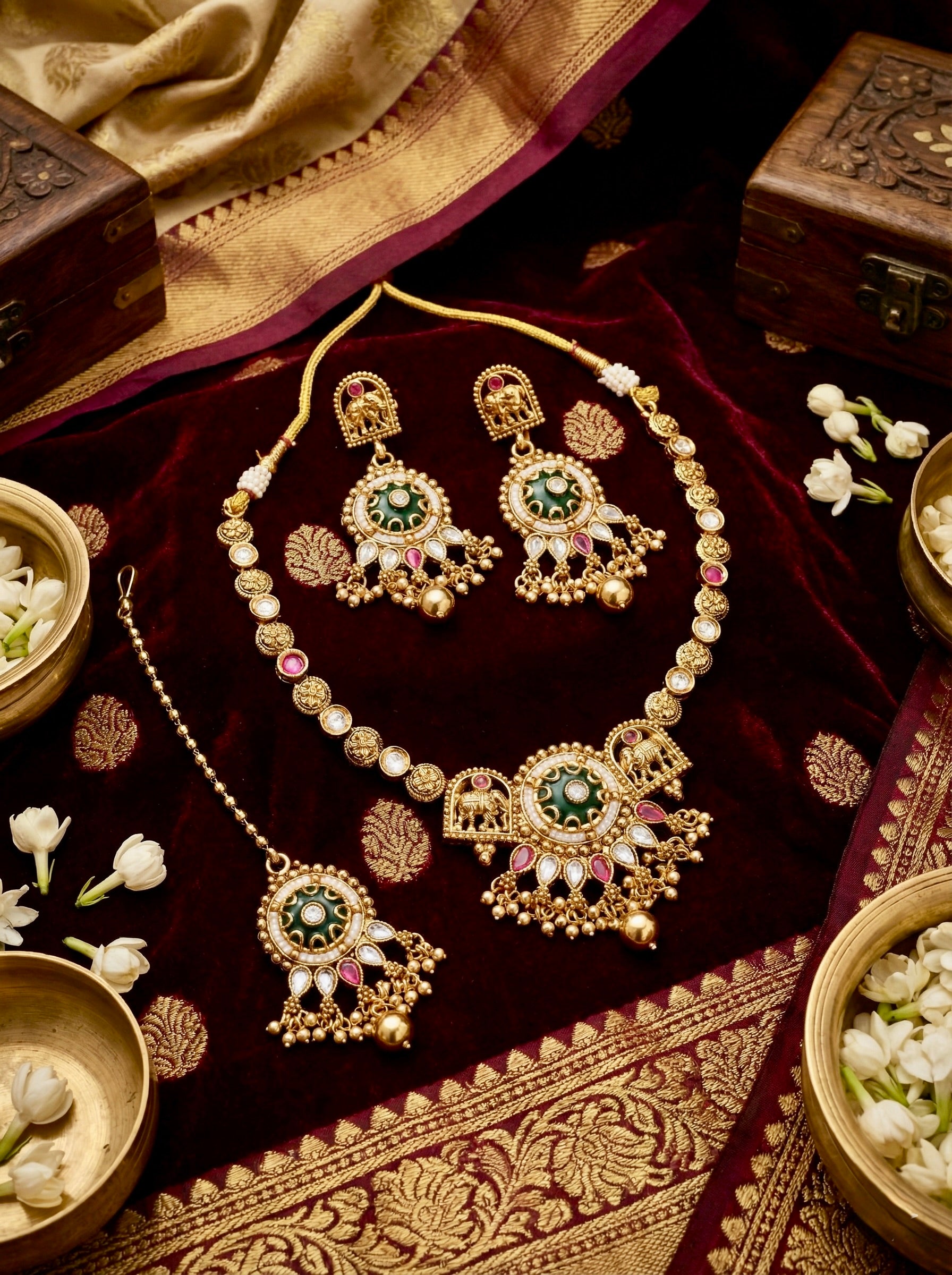 Antique gold-plated temple jewellery set featuring green meenakari work and elephant motifs, including necklace, earrings, and maang tikka.