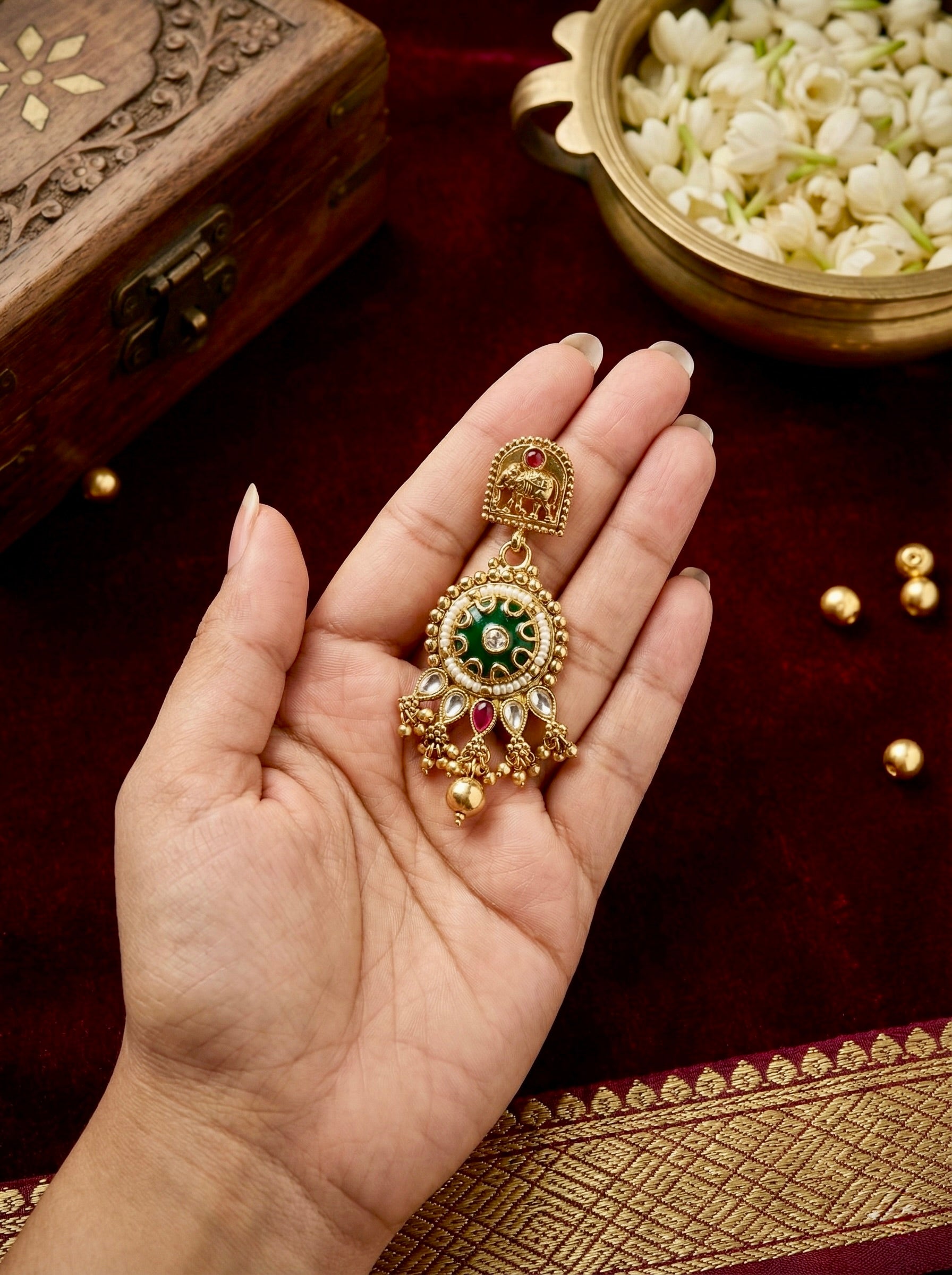 Close-up of matching antique gold kundan earrings with green stone accents