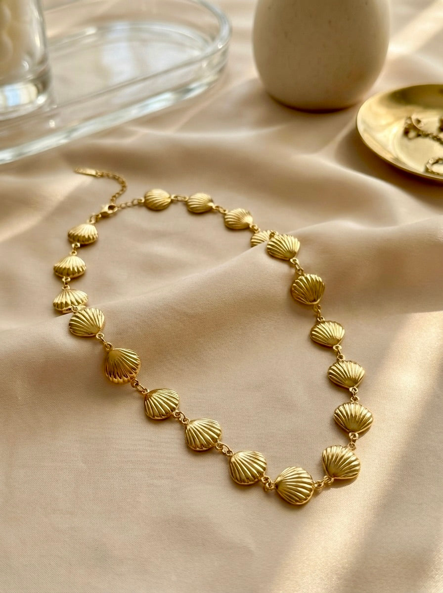 Flatlay of Sephira gold shell link necklace styled for everyday elegance