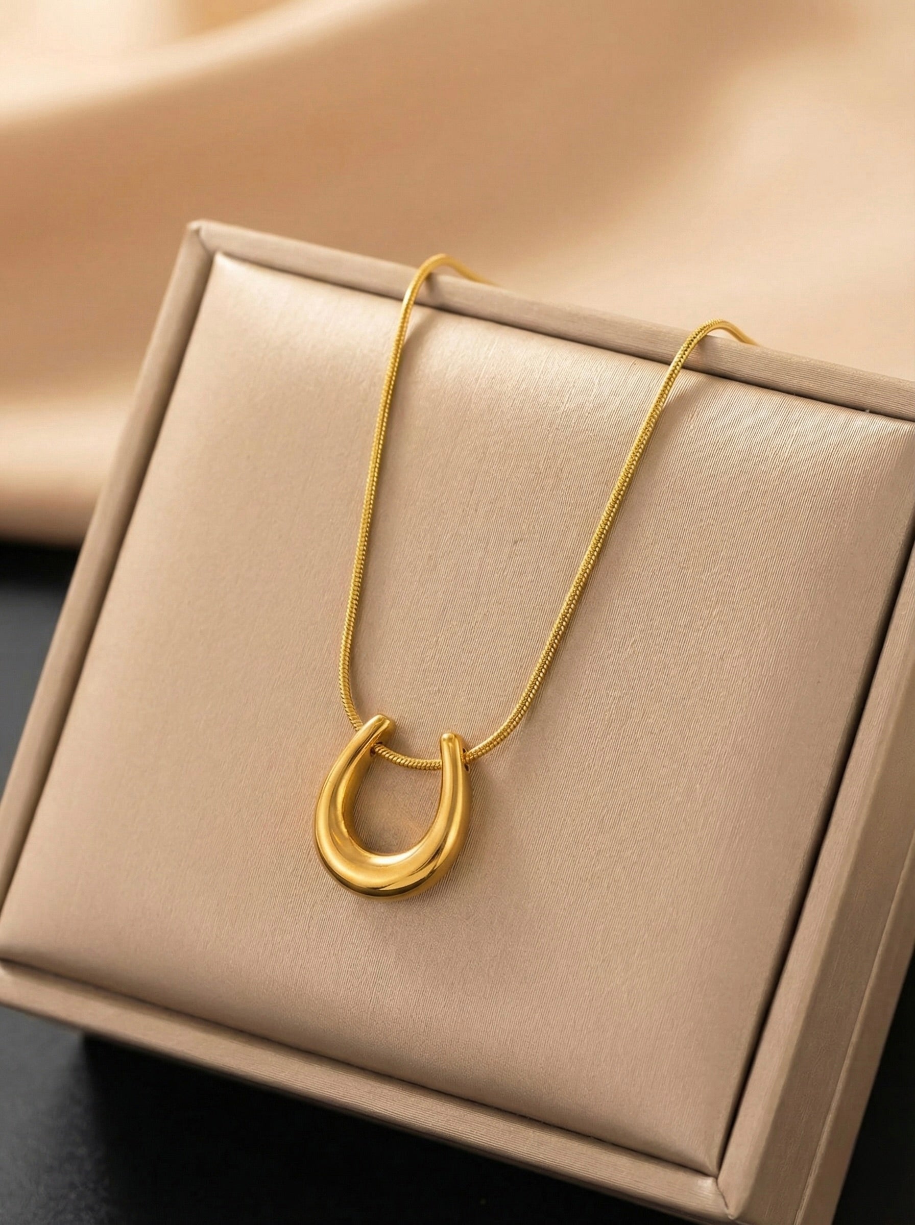Side view of minimal gold U-shaped pendant necklace design
