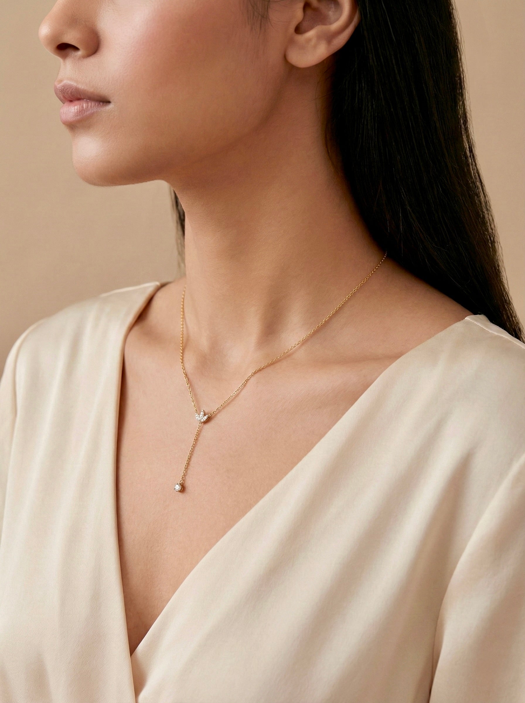 Close-up of sparkling CZ on gold dropline Y necklace on model with side view. Elegant anti-tarnish gold necklace with CZ accents  