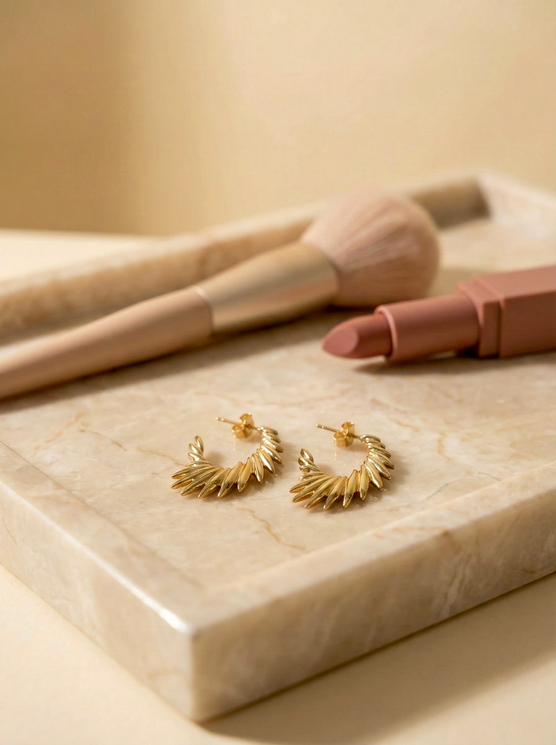 Zarielle Sunburst gold hoop earrings on flatlay styled for everyday and evening looks