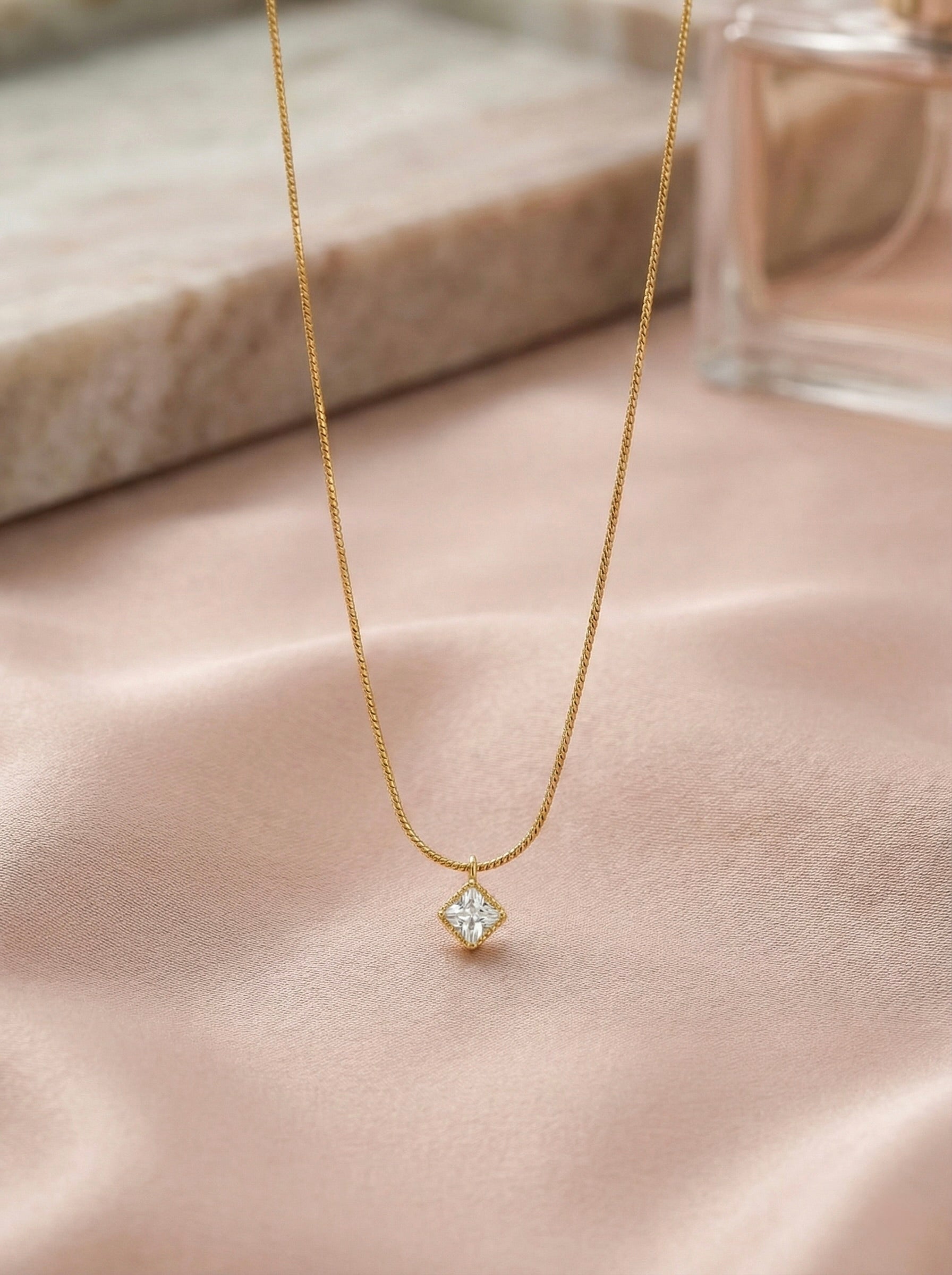 Close-up of zyelle square CZ solitaire stone on gold minimal pendant